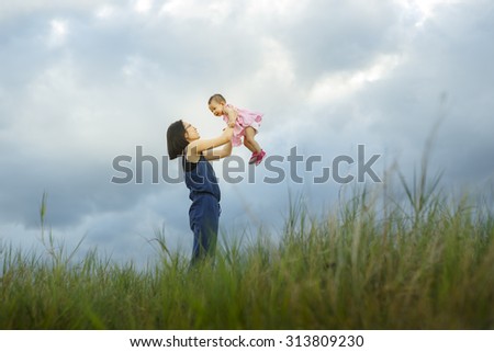 Mother and new born playing on the garden at the sunset time. Concept of friendly family - Vibrant color effect