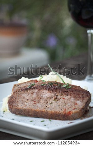 Slice of homemade meat loaf with mashed potatoes and wine sauce