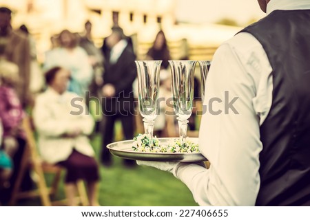 Waiter with glasses on the tray at wedding ceremony, waiting for champagne