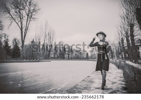 Young pretty sexy lady in black dress outdoor with frozen lake onbackground, black and white
