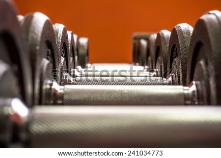Line of dumbbells in the gym on orange background