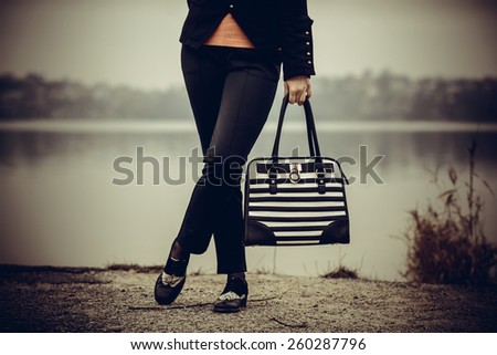 Girl in black and white shoes with black and white bag in her hands outdoor