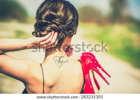 Barefoot brunette girl outdoor with red high heels in her hands