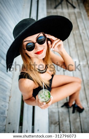 Young pretty sexy girl drinking cold beverage outdoor in beach cafe