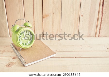 Alarm clock and notebook on wooden table over wood background, Still life style