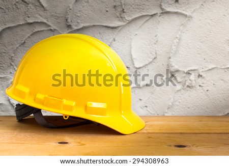 Yellow Safety Helmet on Wooden Floor with Cement Wall Background , color pop tone