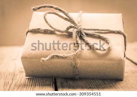 Vintage gift box brown paper wrapped with rope on wood background , antique tone