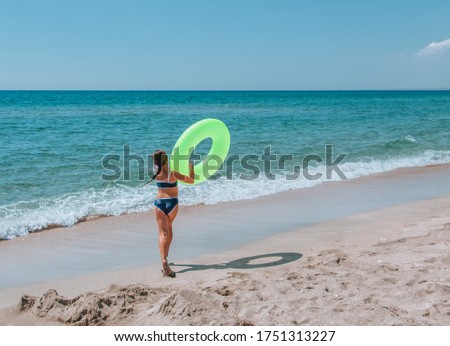stock photo back view of happy cute brunette girl in a blue swimsuit going to swim in clear azure sea with 1751313227