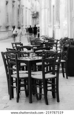 Lecce, IT, August 15, 2014: chairs and tables outside a bar. Horizontal black and white