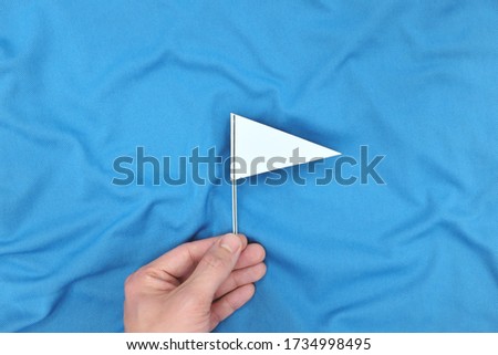 Hand holding a white flag in blue background. Peace, ceasefire, surrender and truce concept. Stock fotó © 