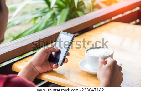 man drink coffee and use smart phone in coffee shop at evening
