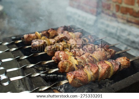 Preparation of a shish kebab on the grill in the yard of a private house on a rainy day. Skewer outdoors. Family traditions.