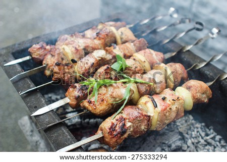 Preparation of a shish kebab on the grill in the yard of a private house on a rainy day. Skewer outdoors. Family traditions.