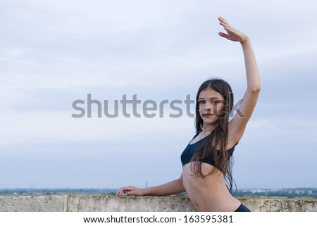 girl practicing ballet on the terrace, outdoor portrait with hand raised