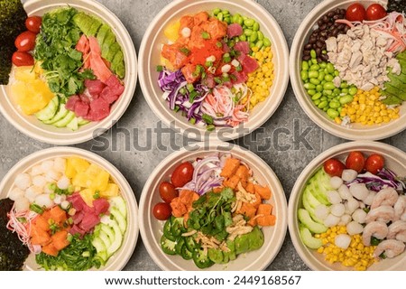 Foto Bild Japans Poke Bowl mit Meeresfrüchten und Salat und vegane Schale mit Gemüse und Kichererbsen in nachhaltigen Lebensmittelbehälter auf grauem Hintergrund. Umweltfreundliche Lieferung von Lebensmitteln mit plastikfreiem Besteck. Ansicht von oben.