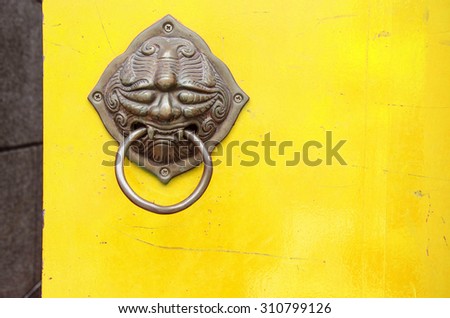 chinese temple ,yellow wood door  metal knocker lion handle, decoration of