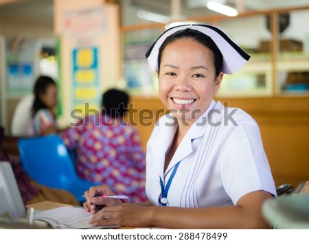 UDONTHANI THAILAND-JUNE 18 2015: Asia nurse: Woman nurse smiling while working at hospital writing medical report.