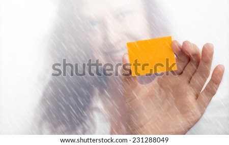Girl\'s blurry face and hand with a yellow slip of paper in the rain