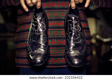 Close view of an old black men\'s shoes in a men\'s hands