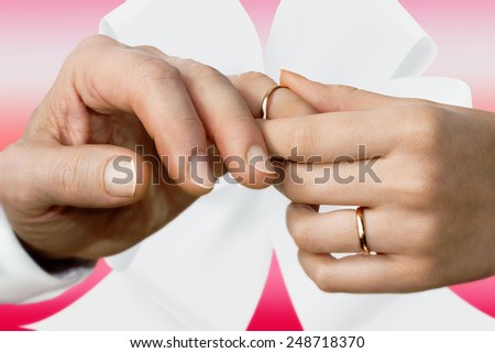 Close view of a woman\'s hand putting on a wedding ring on a man\'s finger