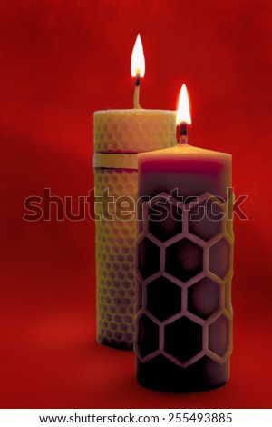 Close view of two beeswax candles flame on a red background