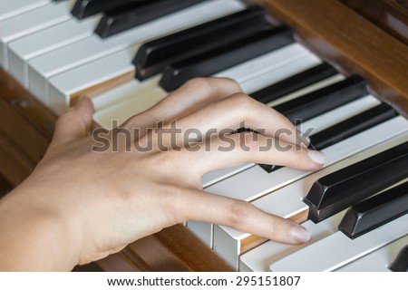 Close view of  girl\'s right hand finger holding pressed  keys on a piano
