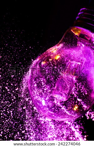 Abstract Purple colorful light bulb with powder on black background close up
