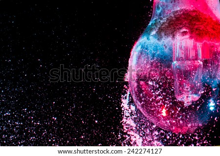 Abstract Purple colorful light bulb with powder on black background