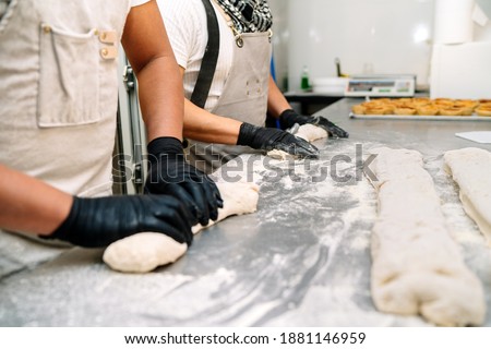 Selective focus of two bakers with black gloves kneading the dough to make bread before putting it in the oven on a baking table Foto stock © 