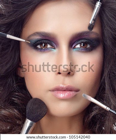 attractive young caucasian woman closeup portrait isolated on white looking at camera studio shot face macro skin makeup eyes hands brushes