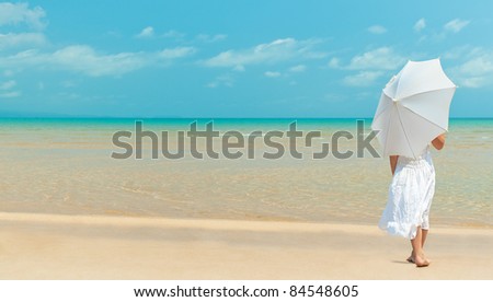 girl standing back on the beach  in white dress with umbrella