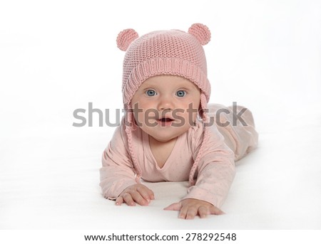 baby girl child lying down on white blanket smiling happy pink fashion portrait face studio shot isolated on white caucasian