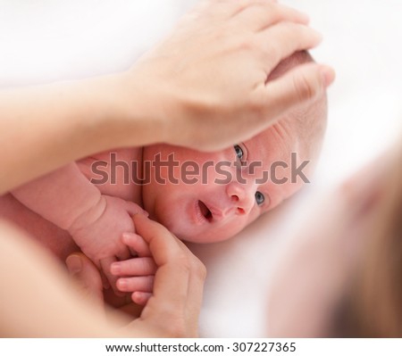 newborn baby looking at mother mother\'s hands face eyes little child care love