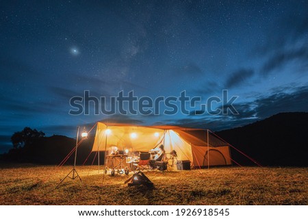 Tourists in yellow tent camping on hill with milky way in the night sky at national park