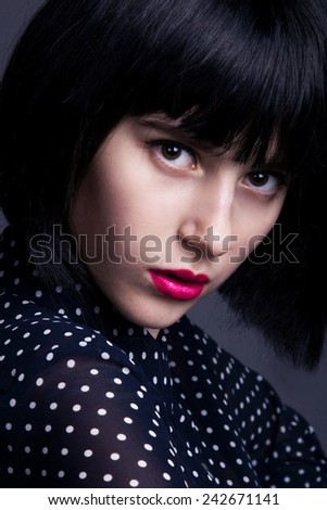 Beautiful cute woman in a black wig and the black shirt  polka dot. Perfect makeup. Closeup. Pink lips.