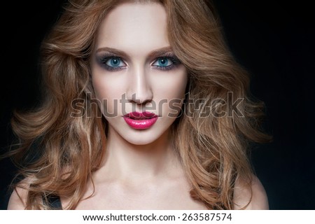 Portrait of beautiful blond woman with pink lips. Curly long hair. Studio shot. Black background