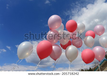 Balloons on ribbons against the sky and clouds