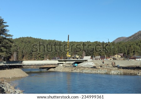 Construction of the bridge through the river in the mountain village in Altai,Russia