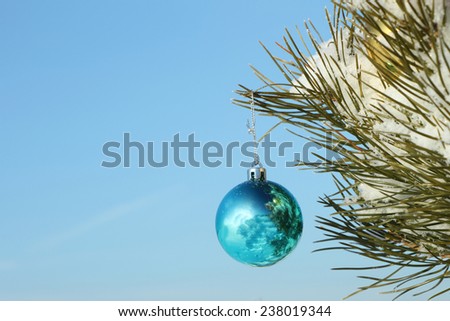 The blue sphere hanging on a Christmas tree against the sky
