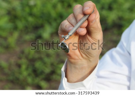 Hand of the doctor in a white form holding a medical mirror outdoors