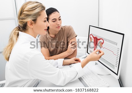 gynecologist communicates with her patient, indicating the menstrual cycle on the monitor. The reproductive specialist calculated the period of ovulation for the patient