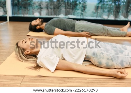Shavasana. Man with woman wearing in sportswear practice yoga while lying down in savasana or corpse pose at wellness center Foto stock © 
