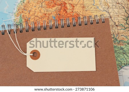 Travel planning concept with blank hang tag on journal and map with copy space