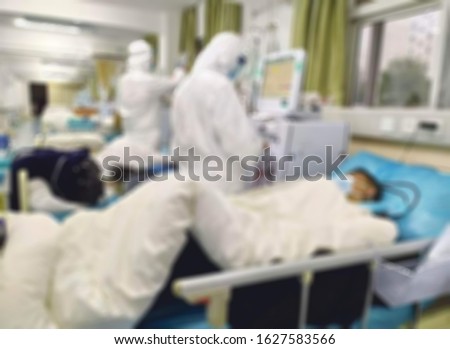 Paramedics working to isolated corona virus suspect in blurry view. viruses that include the common cold, and viruses such as SARS and MERS. This new virus was  named "COVID - 19"
