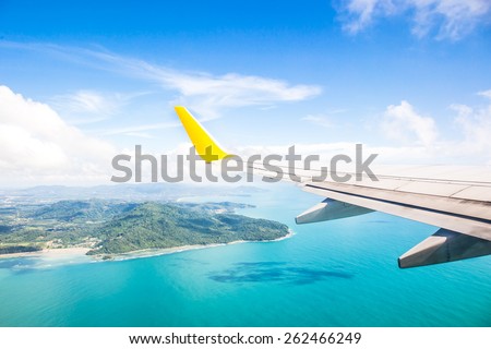 Wing of an airplane flying above the ocean