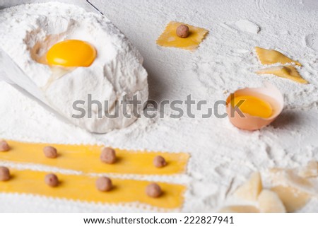 Handmade tortellini recipe. hands making tortellini fresh pasta, eggs and flour on a kitchen table.