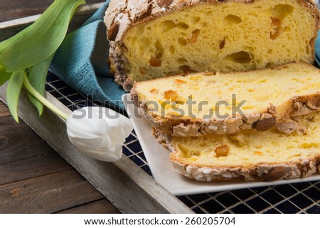 Colomba cake is a typical italian easter cake, takes this name for the form of a dove. Slices of Colomba Pasquale cake on a tray put on a wood table.