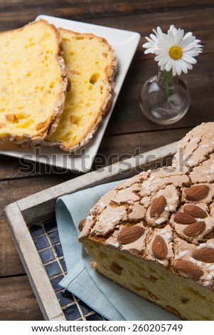 Colomba cake is a typical italian easter cake, takes this name for the form of a dove. Slices of Colomba Pasquale cake on a tray put on a wood table.