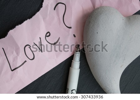 Hand-written text Love? one pencil and one heart of stone