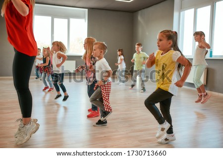 Group of little boys and girls dancing while having choreography class in the dance studio. Female dance teacher and children dancing. Contemp dance. Hip hop. Kids and sport. Full length